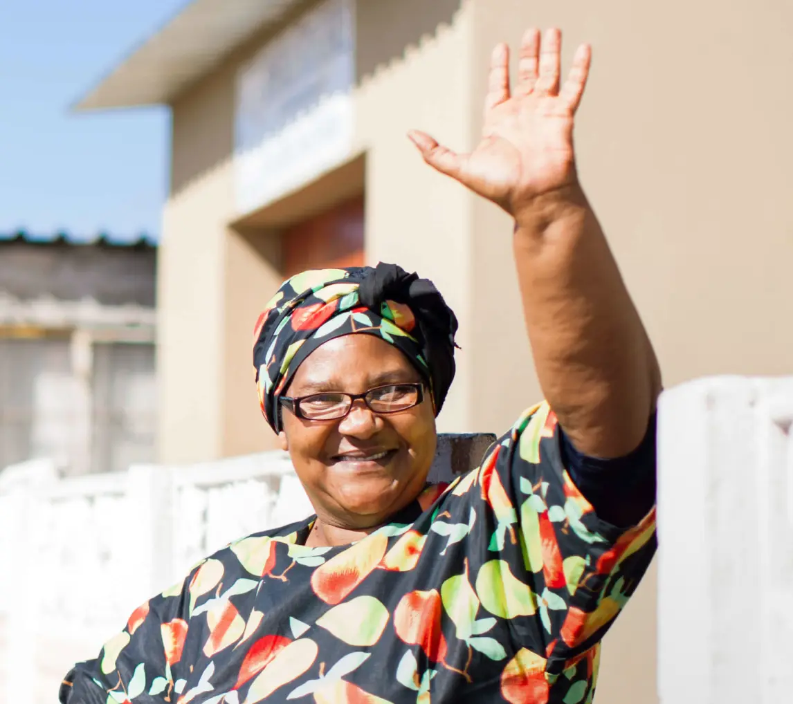 An older lady wearing glasses waving